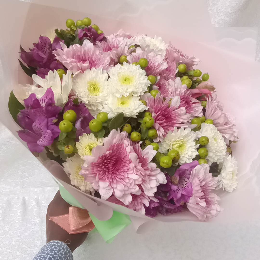 Decorative Hand Bouquet by Simona Flowers Kenya, is a perfect mix of beautiful lavender, green and white tropical flowers and wrapped to match the mood of the occasion. Flowers included are: Chrysanthemums Hypericus Alstroemeria and seasonal flower fillers