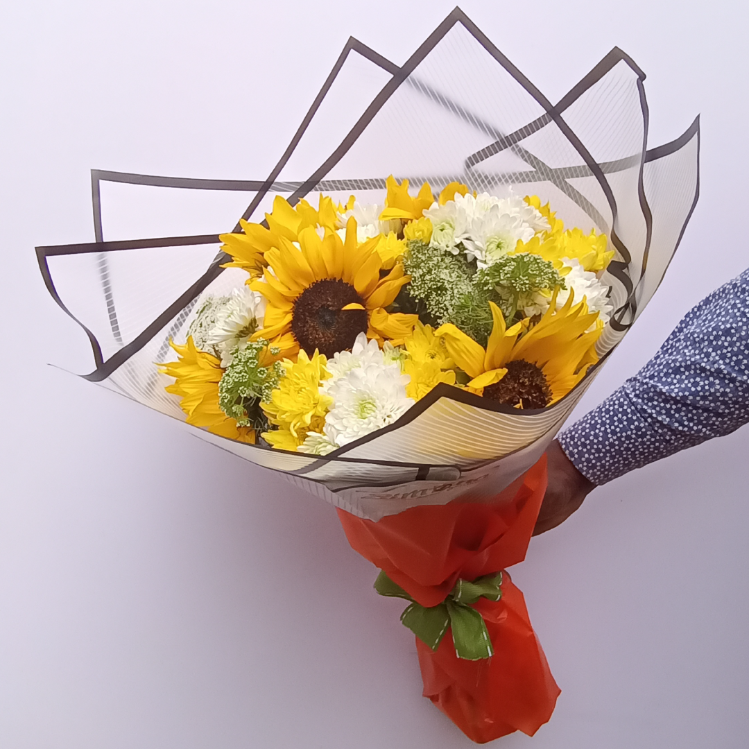 Simona Flowers - The Jolly Bouquet is a bright assortment of joy with: Sunflowers, Chrysanthemums and Various flower fillers.