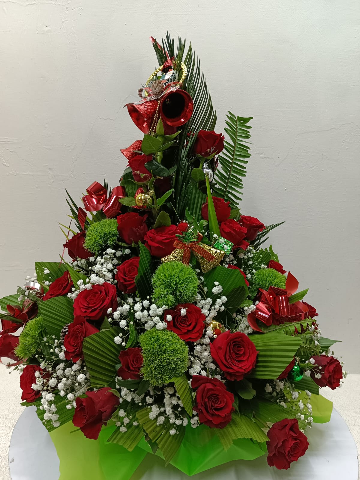 Floral arrangement resembling a Christmas tree with red, green, and white flowers on a white background