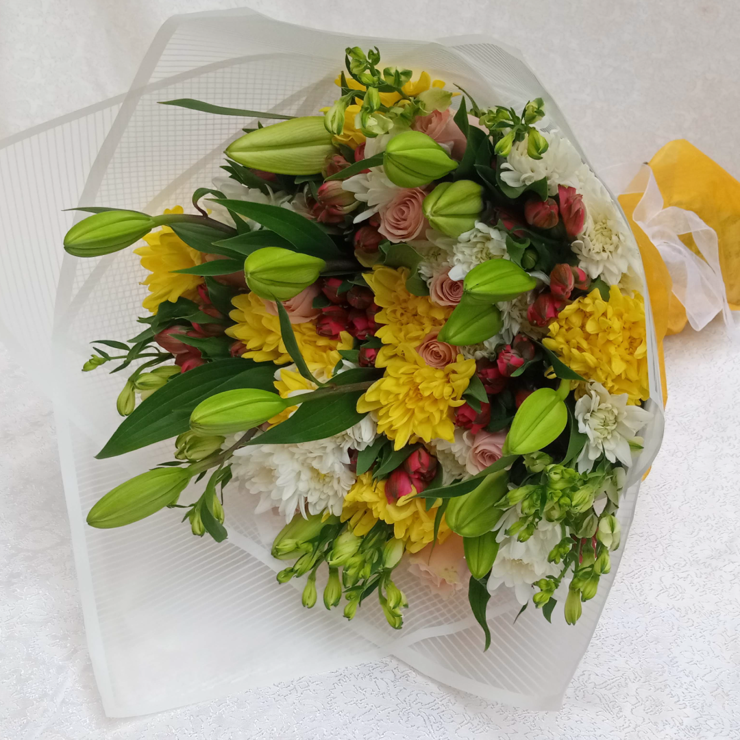 Amber Lily Bouquet by Simona Flowers Kenya, has a touch of:  Lilies Hypericus flowers Yellow Chrysanthemums White Chrysanthemums With a side of flower fillers. The bouquet is wrapped with a complimenting wrapping material for the perfect occasion.