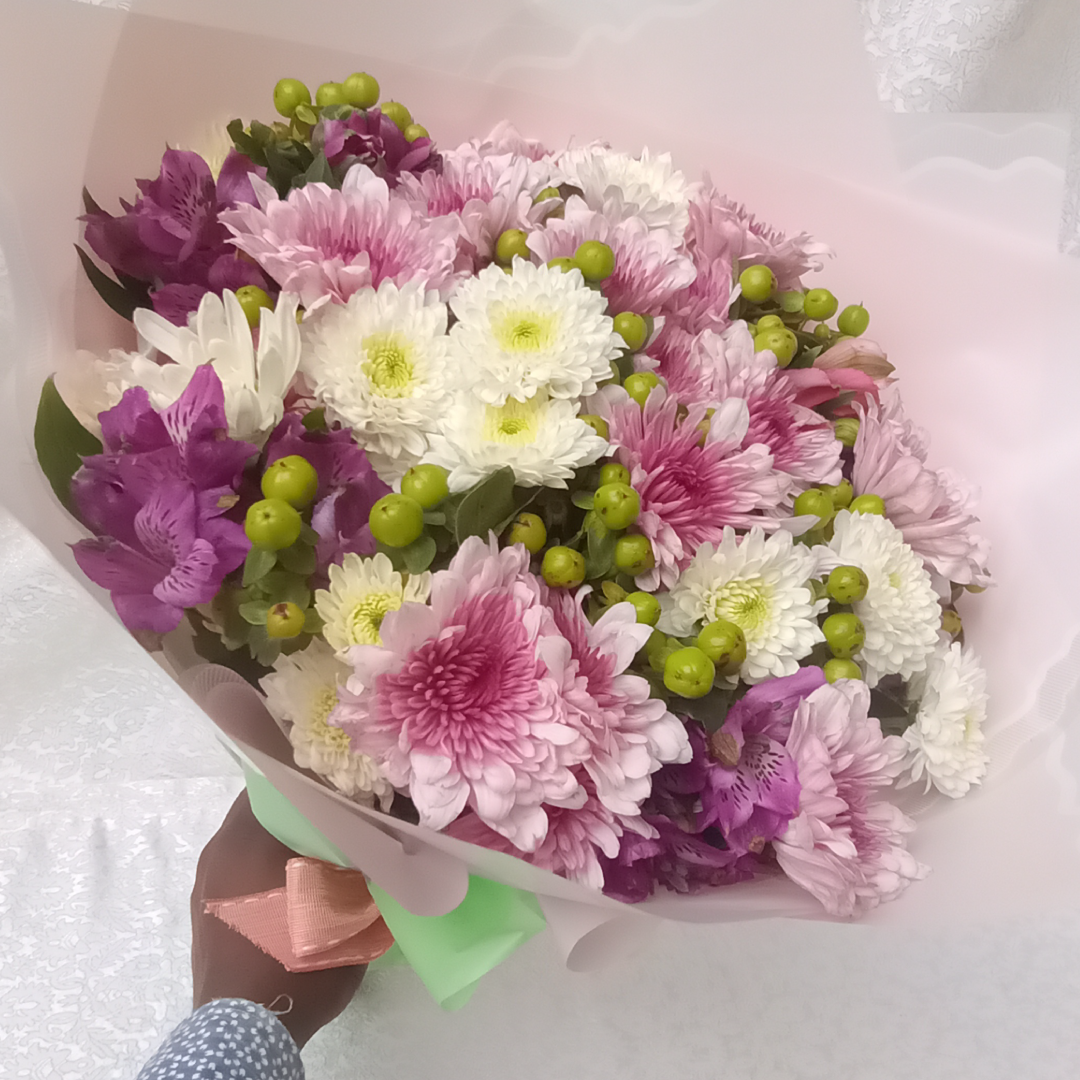 Decorative Hand Bouquet by Simona Flowers Kenya, is a perfect mix of beautiful lavender, green and white tropical flowers and wrapped to match the mood of the occasion.  Flowers included are:  Chrysanthemums Hypericus  Alstroemeria and seasonal flower fillers