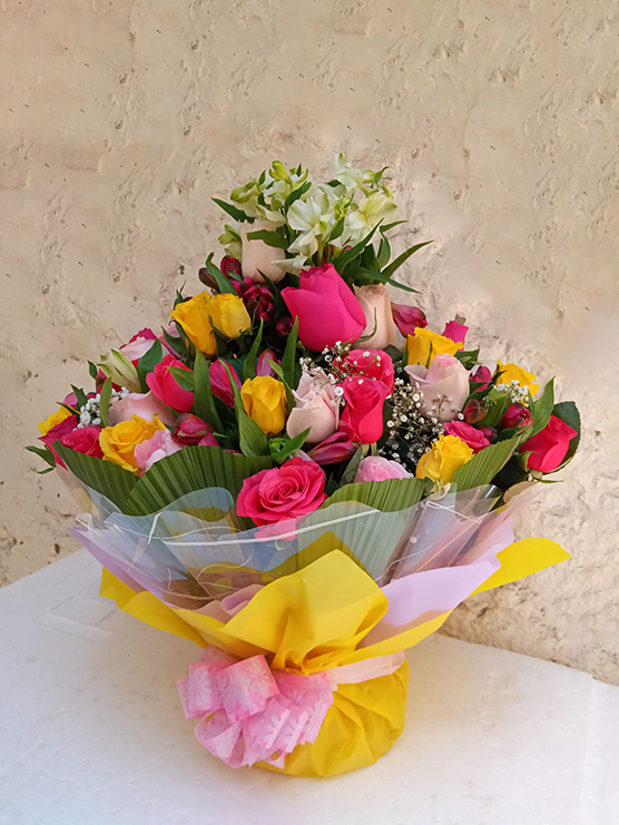 Adorned water bouquet flower arrangement of roses and various flower fillers an beautiful wrapping.