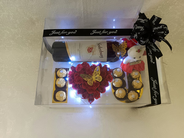 Mapenzi galore package with I ❤️ you arrangement of flowers and chocolate, wine, small teddy and strip lights all in a clear box packaging